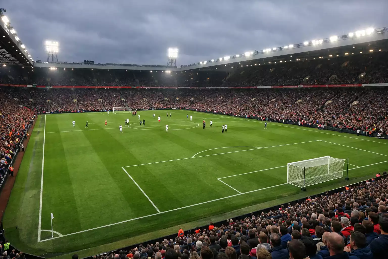 Stade de football anglais rempli de supporters avec une pelouse verte impeccable sous les projecteurs
